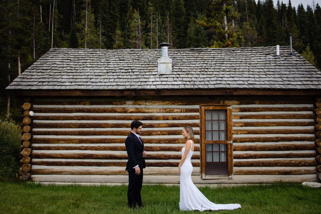 A first look for bride and groom by a rustic log cabin in the Montana west @davidclumpner