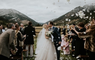 Montana Wedding Venues: A newlywed couple share a kiss amid the mountains at 320 Guest Ranch.