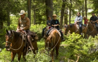 Montana Horseback Riding: A group of people being led by an experienced wrangler traverse a forest trail near 320 Guest Ranch in Gallatin Gateway, MT.